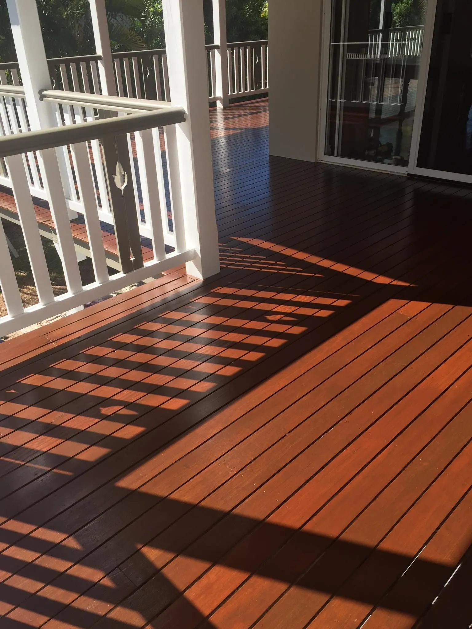 Cairns timber deck restored with a rich warm stain beside white balustrades