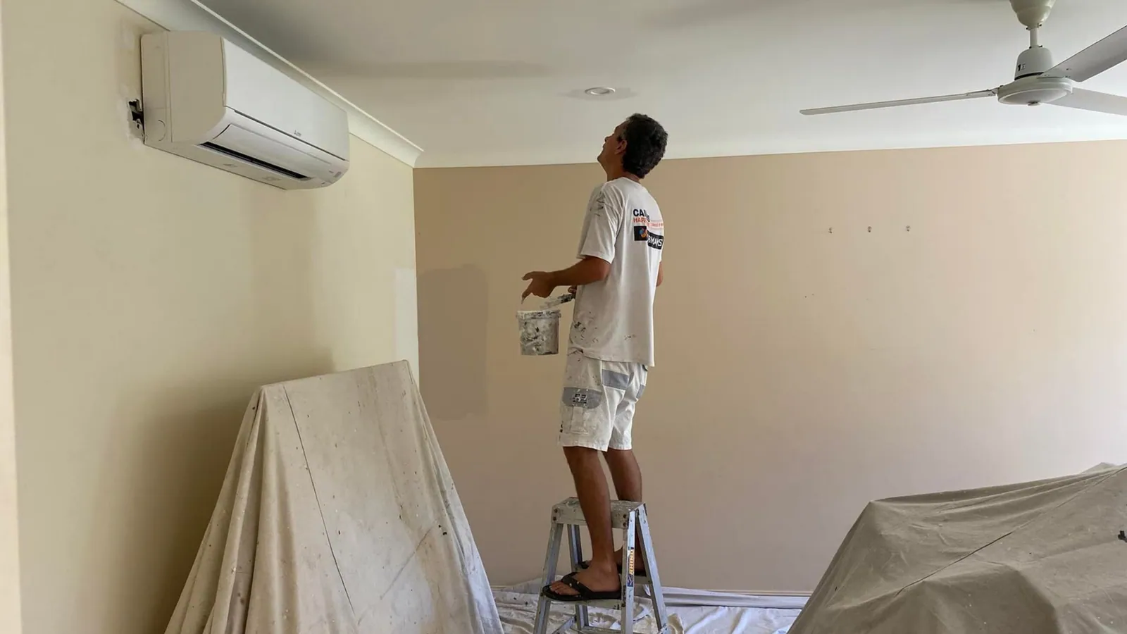 Painter preparing the exterior of a Cairns home before painting